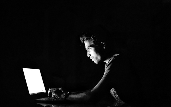Man in dark room working on laptop